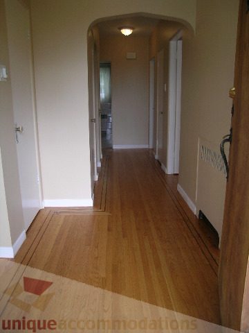Bright hallway with hardwood floors and arched doorway leading to another room. - 1561 Jefferson Ave, West Vancouver