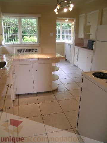 Bright kitchen with light countertops and tiled flooring, featuring a large window with a view. - 1561 Jefferson Ave, West Vancouver