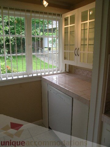 Bright kitchen with white cabinets, granite countertops, and a view of the garden. - 1561 Jefferson Ave, West Vancouver