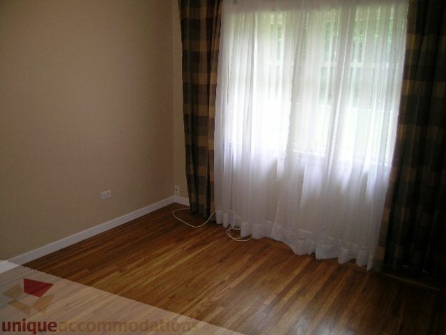Bright living room with hardwood floors and large windows with sheer curtains. - 1561 Jefferson Ave, West Vancouver