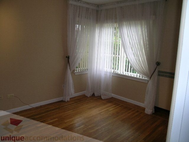 Bright living room with hardwood floors and sheer curtains. - 1561 Jefferson Ave, West Vancouver