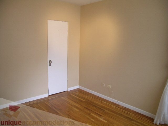 Empty bedroom with hardwood floors and white door. - 1561 Jefferson Ave, West Vancouver