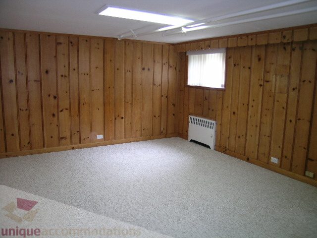 Spacious bedroom with wood-paneled walls and carpeted floor. - 1561 Jefferson Ave, West Vancouver