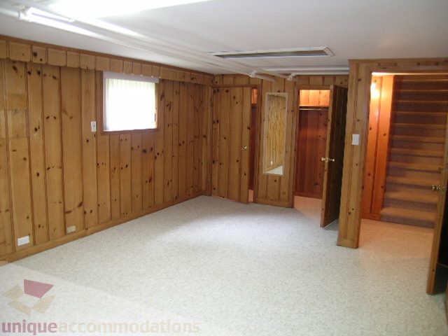 Spacious living room with wooden paneling and carpeted floors. - 1561 Jefferson Ave, West Vancouver