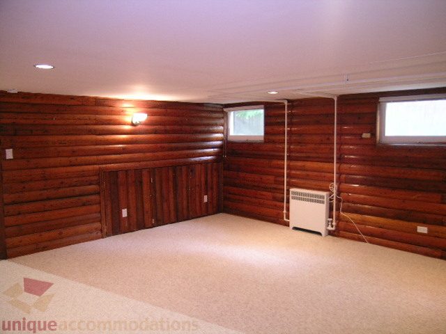 Large, open living room with wooden log walls and carpeted floor. - 1561 Jefferson Ave, West Vancouver