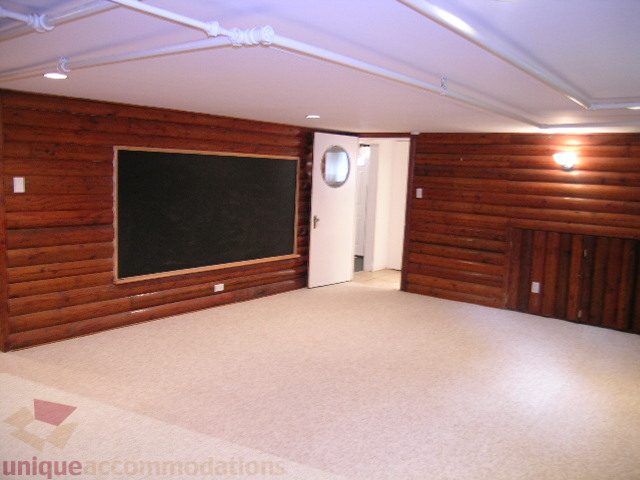 Spacious living room with wooden walls and carpeted floors. - 1561 Jefferson Ave, West Vancouver