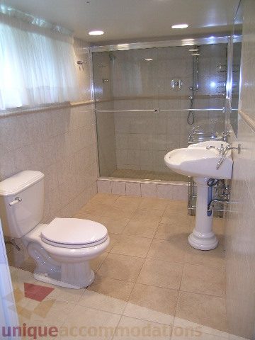 Bright bathroom with beige tiles, modern sink, and glass shower enclosure. - 1561 Jefferson Ave, West Vancouver