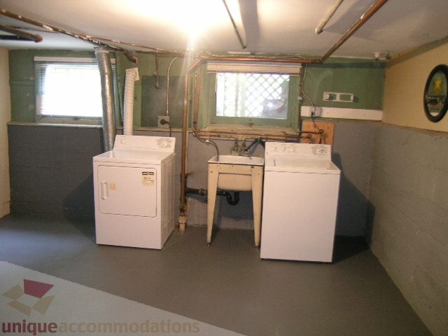 Laundry room with white appliances and exposed pipes. - 1561 Jefferson Ave, West Vancouver
