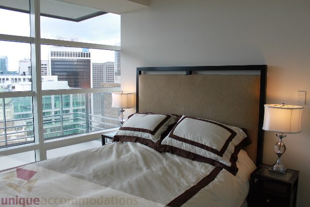 Spacious bedroom with large windows offering a city view, modern furnishings, and a cozy ambiance. - 3304 - 1011 West Cordova, Vancouver Downtown