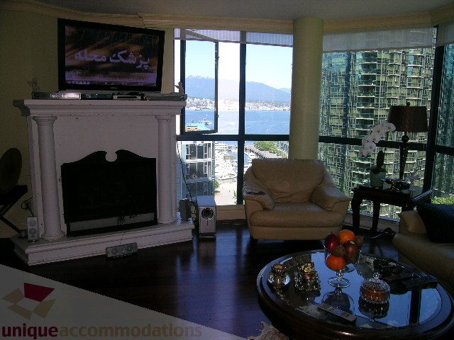 Spacious living room with a stunning city view, hardwood floors, and a cozy fireplace. - 904 - 1415 West Georgia, Vancouver Downtown