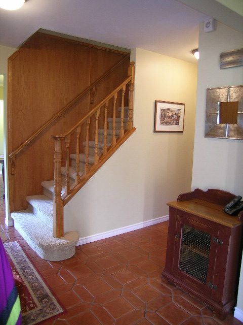 Staircase with wooden banister and terracotta tiled floor. - 5753 Westport Road, West Vancouver