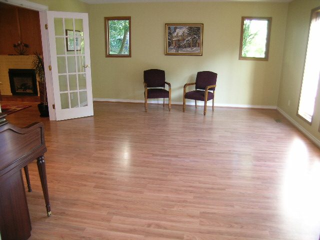 Living room with hardwood floors, two armchairs, and a fireplace. - 5753 Westport Road, West Vancouver