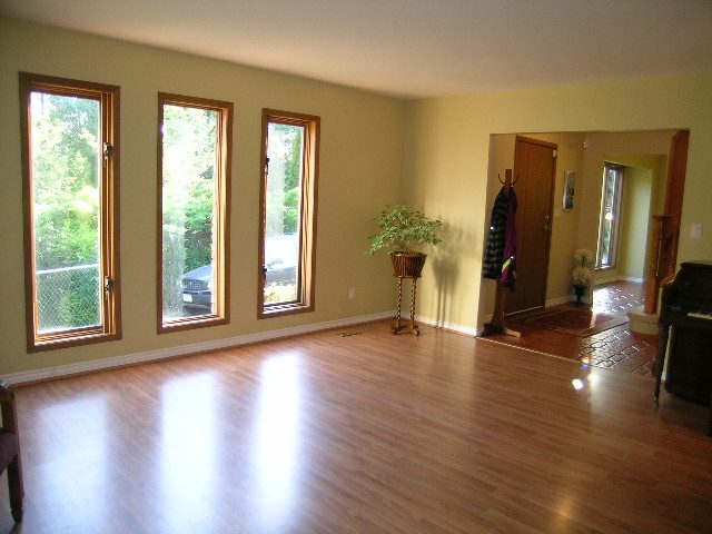Bright dining room with hardwood floors and large windows, leading to a cozy living area. - 5753 Westport Road, West Vancouver