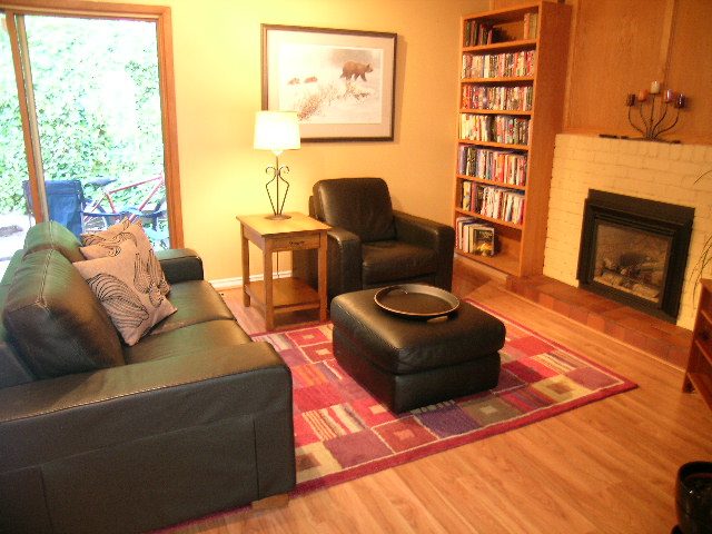 Spacious living room with hardwood floors, cozy leather furniture, and a bookshelf. - 5753 Westport Road, West Vancouver
