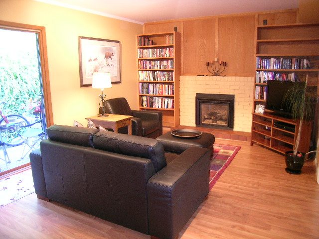 Living room with hardwood floors, bookshelves, and a fireplace. - 5753 Westport Road, West Vancouver