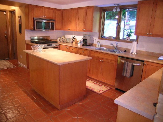 Bright kitchen with light countertops, wooden cabinets, and terracotta tiled floor. - 5753 Westport Road, West Vancouver