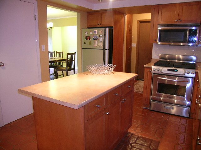 Bright kitchen with granite countertops and stainless steel appliances, leading to a dining area. - 5753 Westport Road, West Vancouver