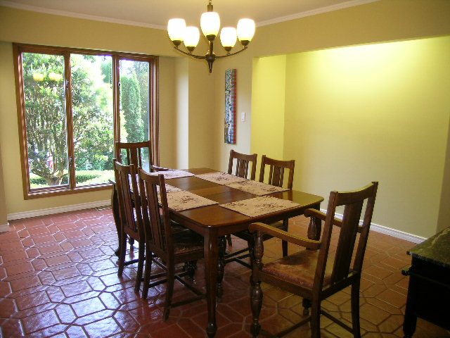 Spacious dining area with wooden table, chairs, and large window view. - 5753 Westport Road, West Vancouver