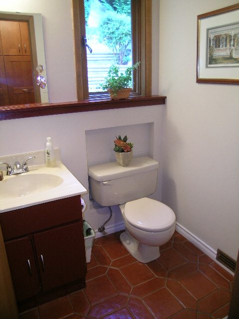 Bright bathroom with terracotta tile floor and a window with a potted plant. - 5753 Westport Road, West Vancouver