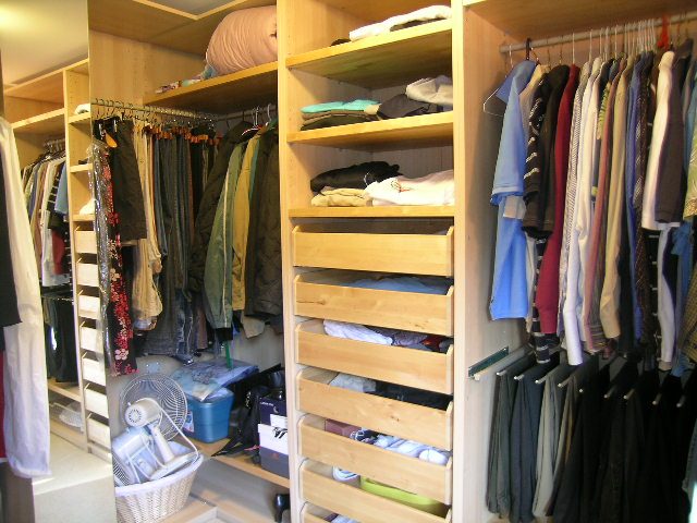 Spacious walk-in closet with wooden shelves and hanging racks, neatly organized with clothes and accessories. - 5753 Westport Road, West Vancouver