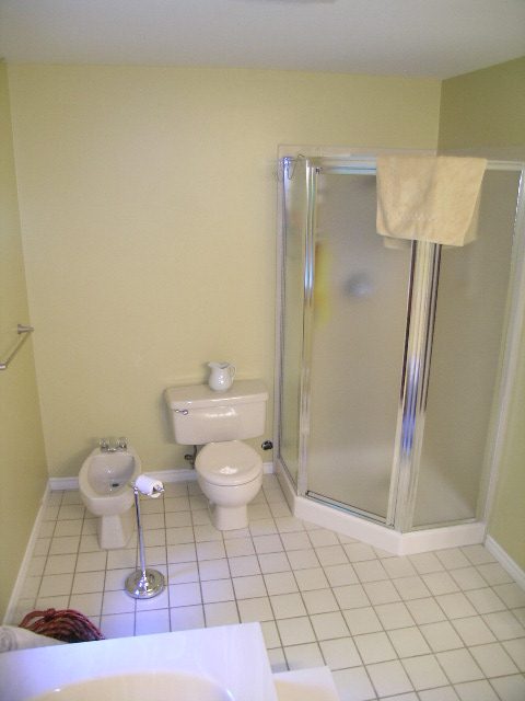 Bathroom with white tile, shower, and toilet. - 5753 Westport Road, West Vancouver