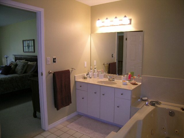 Bright bathroom with white cabinets, countertop, and a bathtub. - 5753 Westport Road, West Vancouver