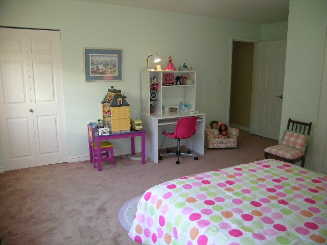Bright bedroom with colorful polka dot bedding and a child's play area featuring a dollhouse and desk. - 5753 Westport Road, West Vancouver