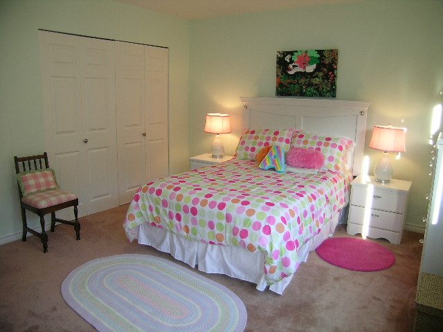 Bright bedroom with colorful polka-dot bedding, pink accents, and a cozy rug. - 5753 Westport Road, West Vancouver