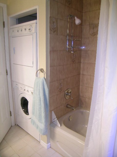 Bathroom with tiled shower, bathtub, and stacked washer/dryer. - 5753 Westport Road, West Vancouver