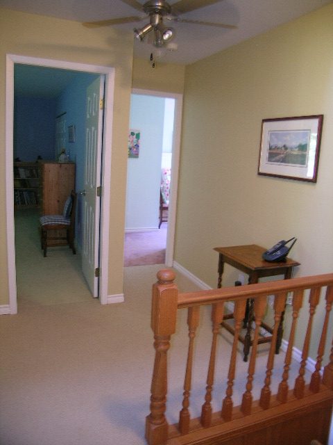 Living area with wooden banister and carpeted floors. - 5753 Westport Road, West Vancouver