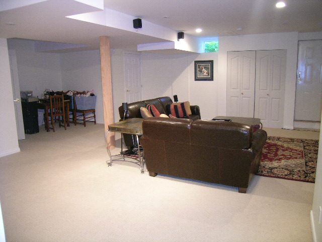 Spacious living room with brown leather couch and patterned rug. - 5753 Westport Road, West Vancouver