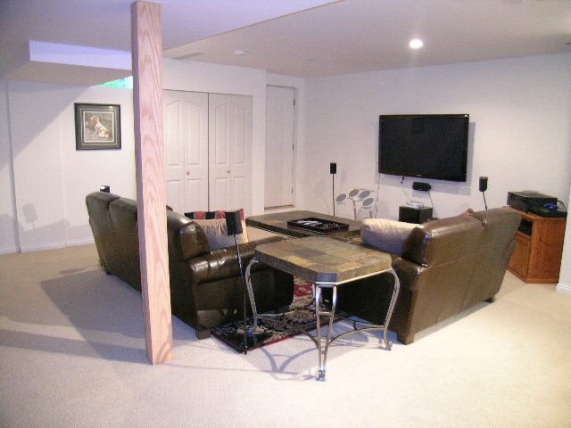 Spacious living room with a large TV, leather furniture, and a carpeted floor. - 5753 Westport Road, West Vancouver