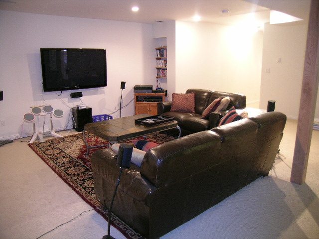 Living room with leather sofas, rug, and mounted TV. - 5753 Westport Road, West Vancouver