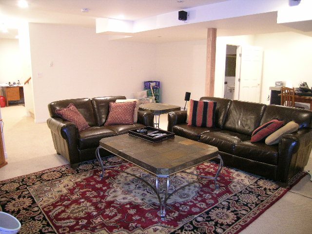 Spacious living room with leather furniture and ornate rug. - 5753 Westport Road, West Vancouver
