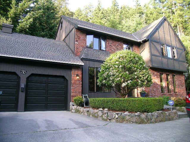 Bright house with dark wood siding, brick accents, and a large front yard. - 5753 Westport Road, West Vancouver
