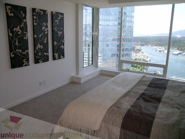 Bright bedroom with city view and modern decor, featuring a large window and a cozy bed. - 3306 - 1011 West Cordova Street, Vancouver Downtown