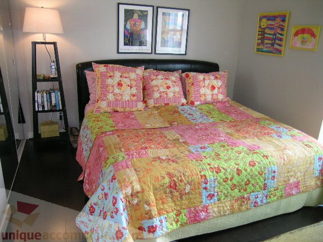 Furnished bedroom with colorful patchwork quilt and framed artwork. - 707 - 638 Beach Crescent, Vancouver Downtown