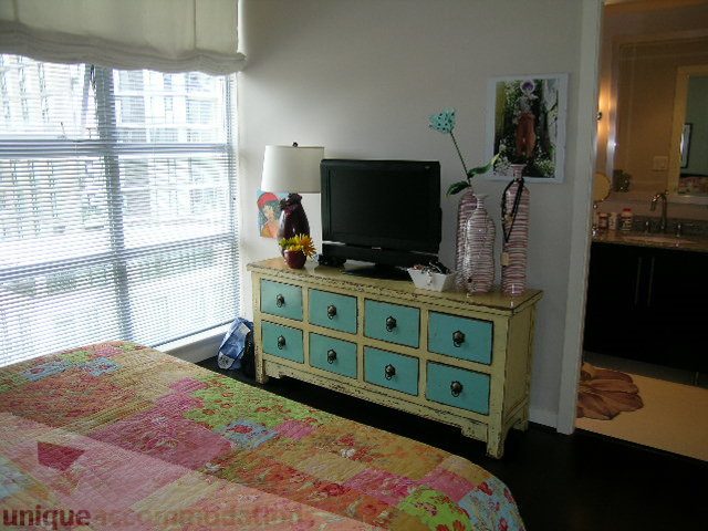 Bright bedroom with patchwork bedspread, teal drawers, and city view through blinds. - 707 - 638 Beach Crescent, Vancouver Downtown