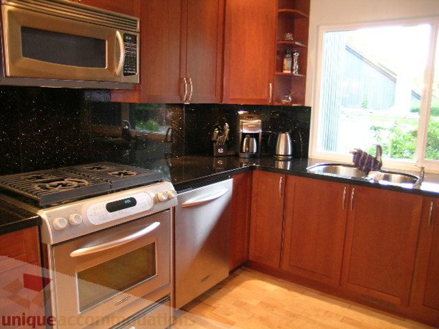 Bright kitchen with wooden cabinets, granite countertops, stainless steel appliances, and hardwood floors.