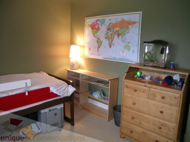Bright bedroom with wooden furniture, desk, and map on wall. - 405 - 4001 Mount Seymour Pkwy, North Vancouver