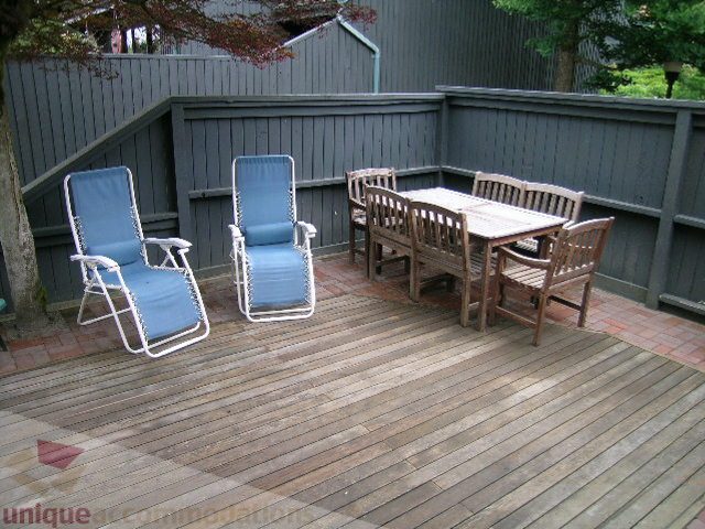 Furnished outdoor deck with wooden table and chairs, surrounded by privacy wall and trees. - 405 - 4001 Mount Seymour Pkwy, North Vancouver