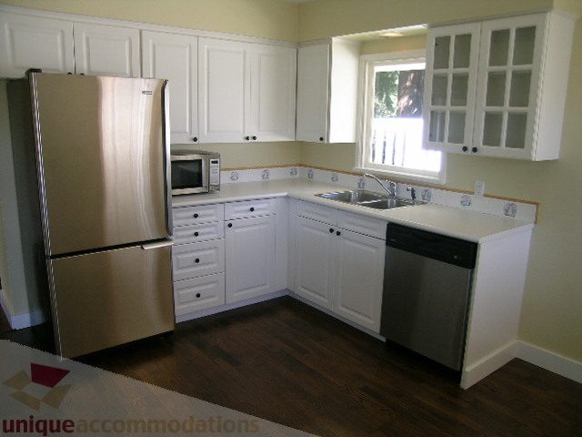 Bright kitchen with white cabinets, stainless steel appliances, and hardwood floors. - 1350 14th Street, West Vancouver