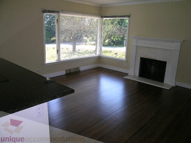 Bright living room with hardwood floors, fireplace, and large windows. - 1350 14th Street, West Vancouver