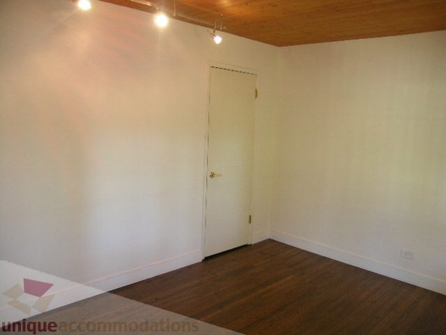Empty living room with hardwood floors and white walls. - 1350 14th Street, West Vancouver