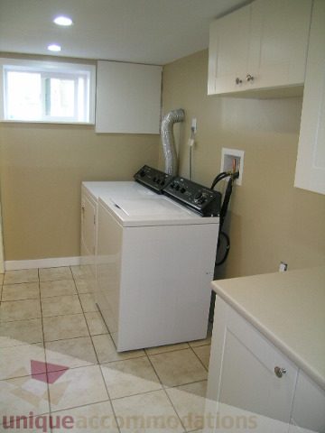 Laundry room with white cabinets, countertop, and tiled floor. - 1350 14th Street, West Vancouver