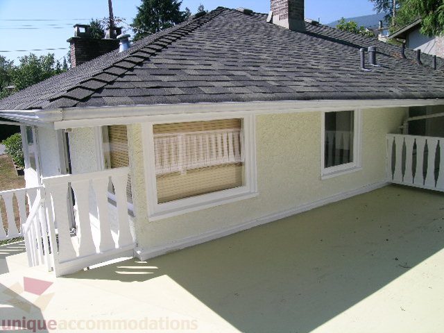 Bright front porch with white railings and beige siding. - 1350 14th Street, West Vancouver