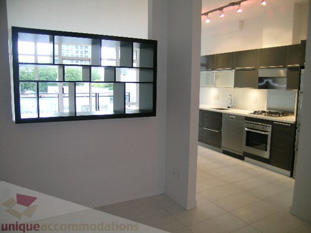 Bright kitchen with stainless steel appliances and a large window offering a city view. - 406 - 1252 Hornby Street, Vancouver Downtown