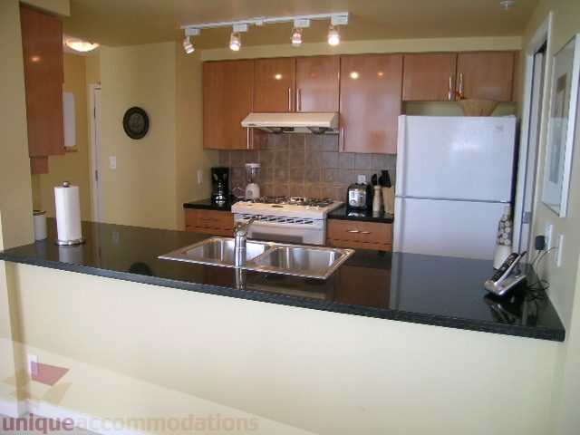 Bright kitchen with granite countertops and stainless steel appliances, featuring a city view. - 1501-1077 Marinaside, Vancouver Downtown