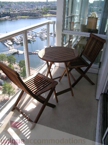 Furnished balcony with wooden furniture and a stunning city view. - 1501-1077 Marinaside, Vancouver Downtown