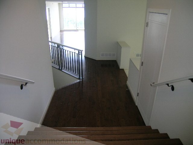 Staircase leading to a bright, open living area with hardwood floors and a view of the outside. - 8601 Seascape Place, West Vancouver